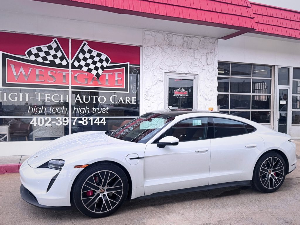 White Porsche Taycan parked outside Westgate High Tech Auto Care in Omaha, Nebraska.